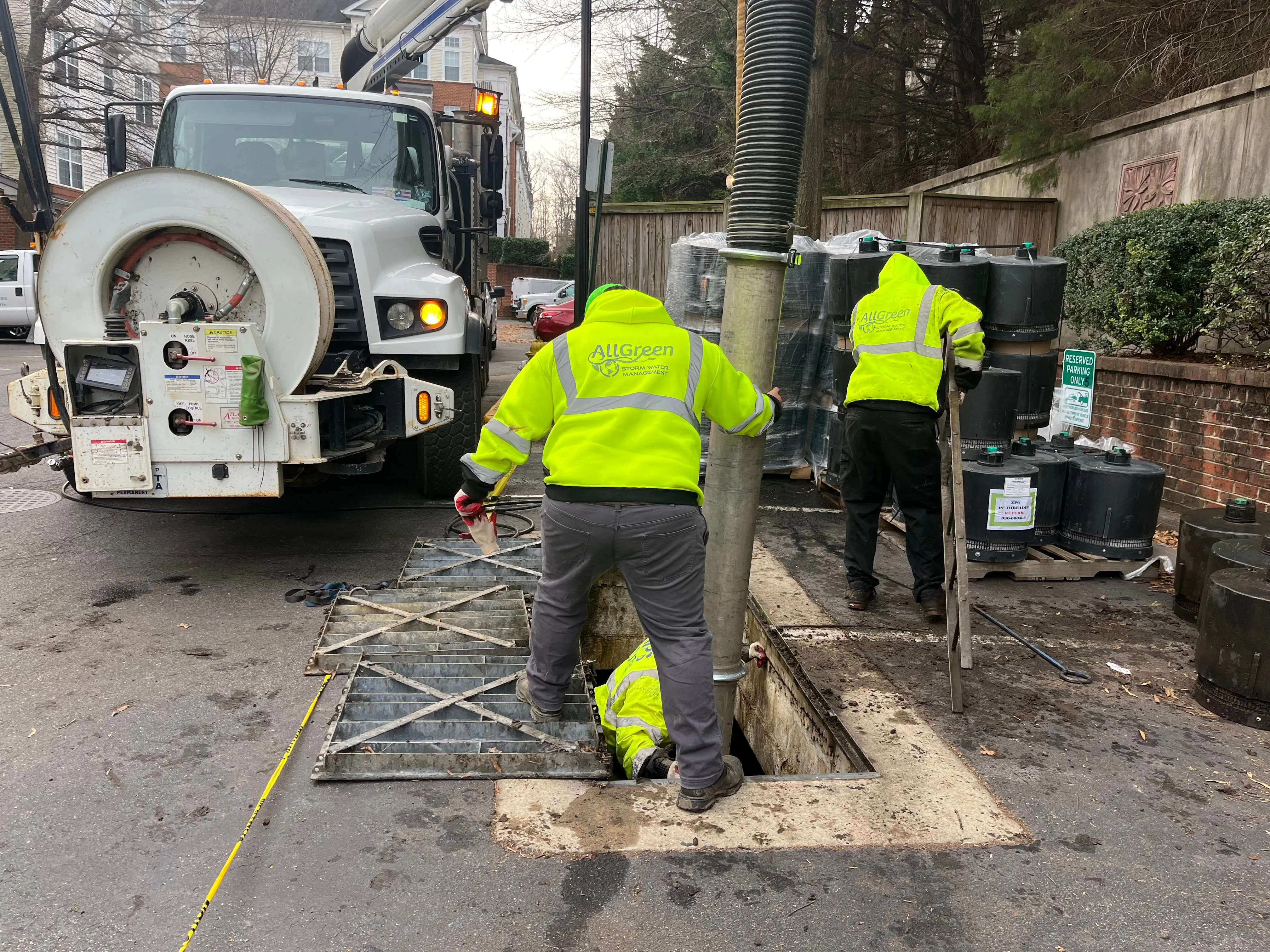 A stormwater technician performing StormFilter vault cleaning and cartridge replacement at a commercial property in Alexandria, VA. The open vault shows removed sediment and a fresh cartridge ready for installation.